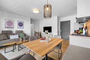 Ein modernes Wohnzimmer mit einem Holzesstisch, grauen Sofas und einem großen Gemälde an der Wand.