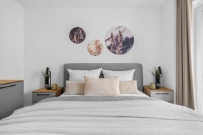 Ein modernes Schlafzimmer mit einem Bett, zwei Nachttischen und Wandbildern.