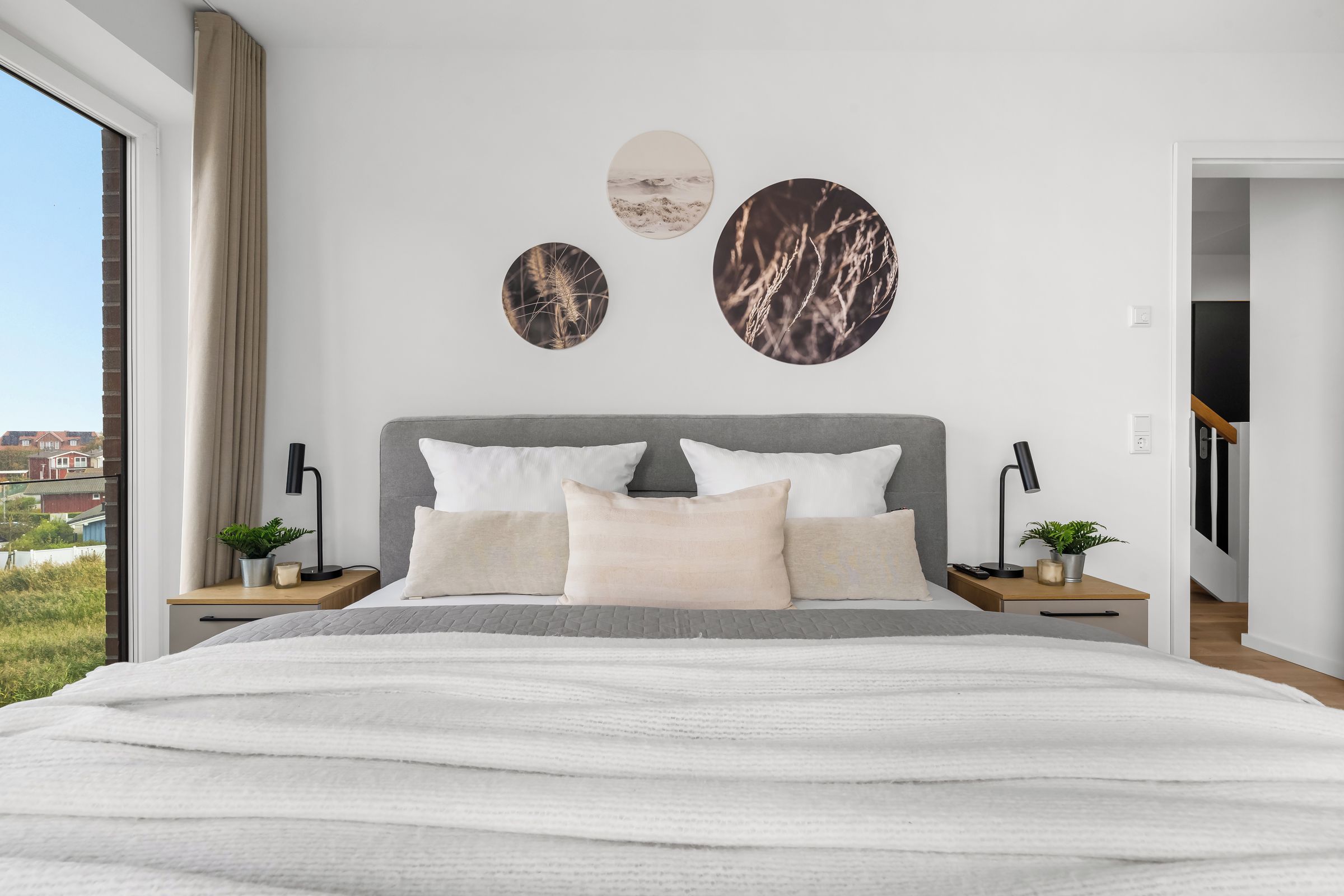 Een moderne slaapkamer met een groot bed, twee nachtkastjes en uitzicht op de omgeving.