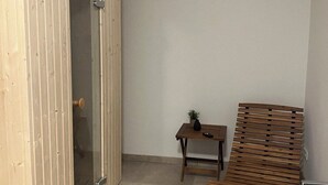 Una habitación con un armario de madera, una mesita con una planta y un banco de madera.