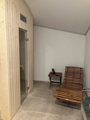 Ein Zimmer mit einem Holzschrank, einem kleinen Tisch mit einer Pflanze und einer hölzernen Bank.