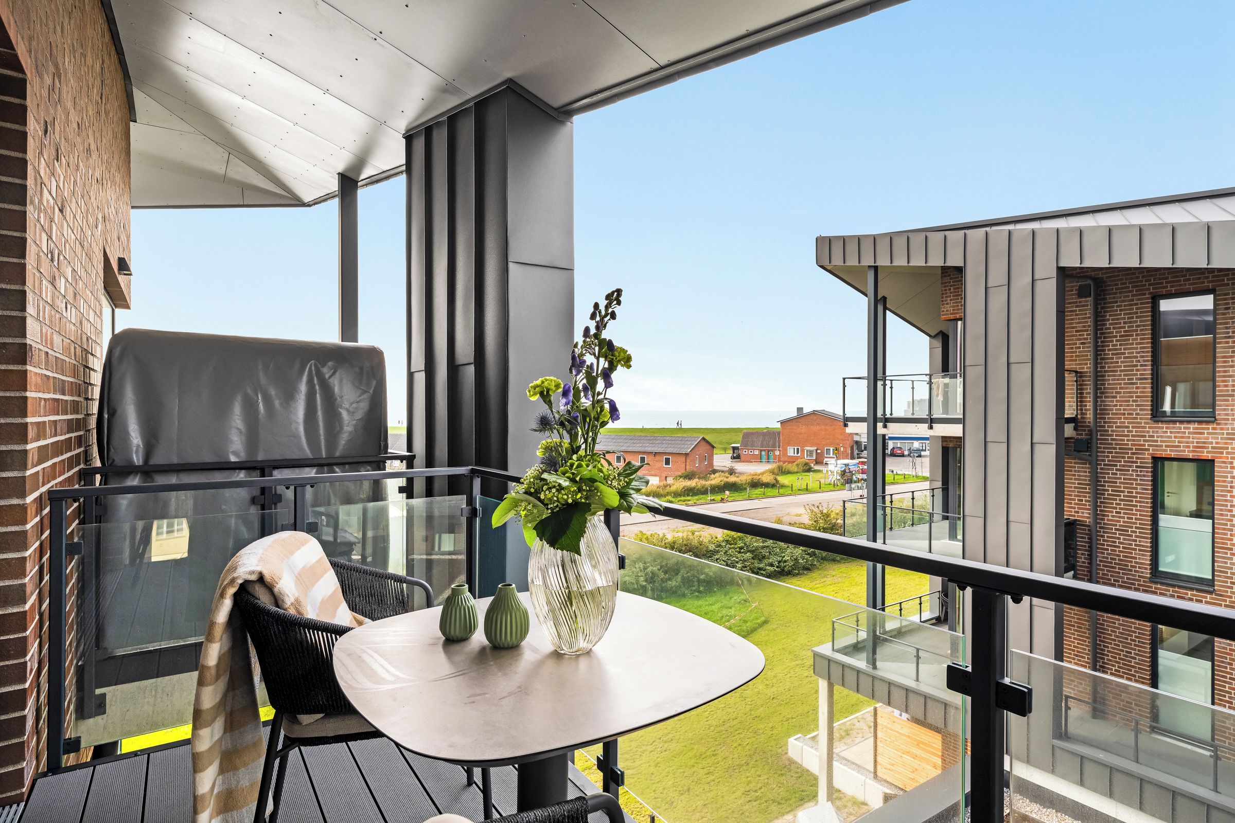 Un balcon avec une table, des chaises et un vase de fleurs.