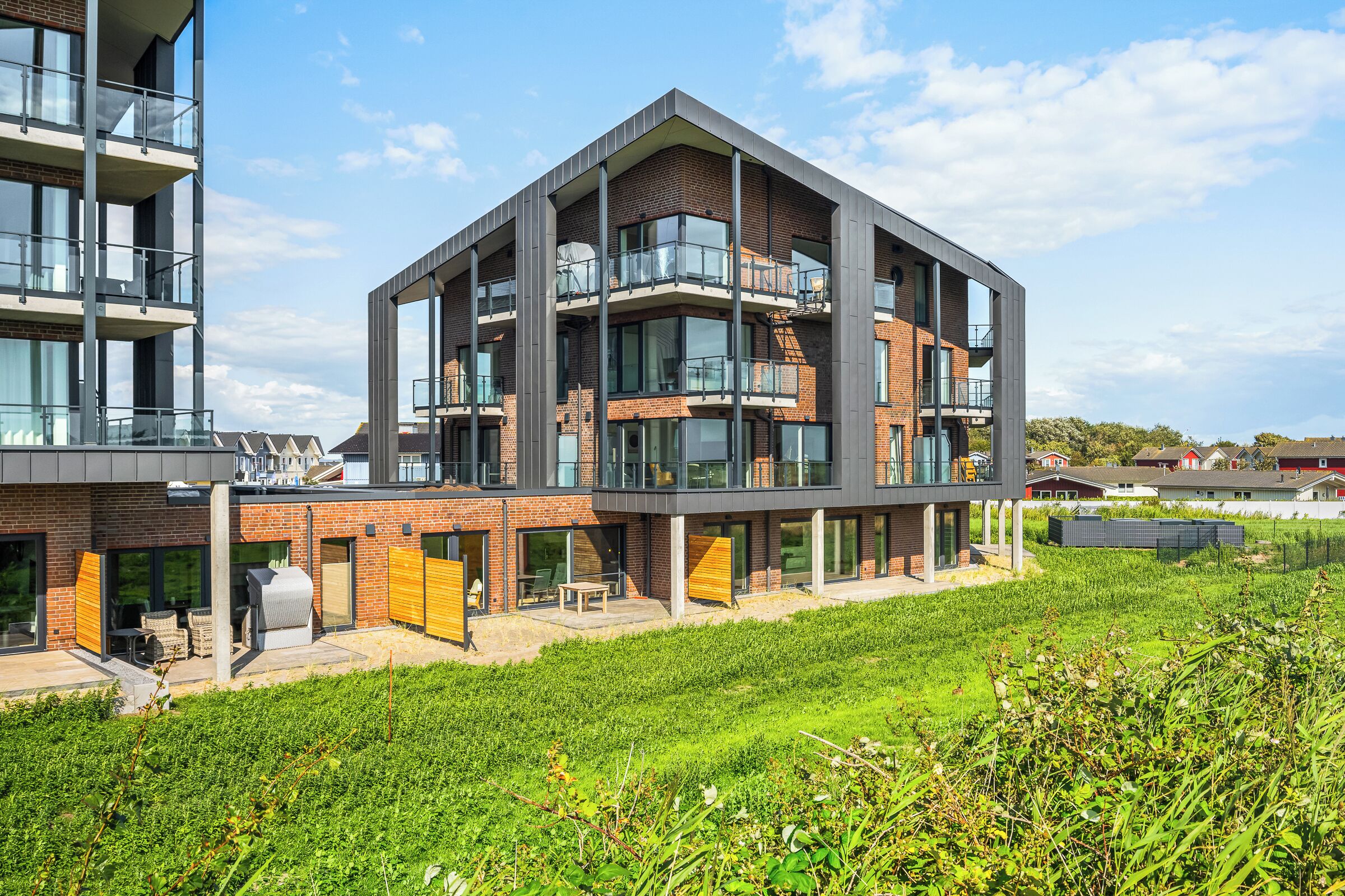 En moderne bygning med flere etager, altaner, store vinduer og et fladt tag.