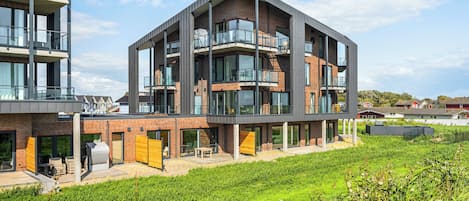 Ein modernes mehrstöckiges Gebäude mit Balkonen, großen Fenstern und einem Flachdach.