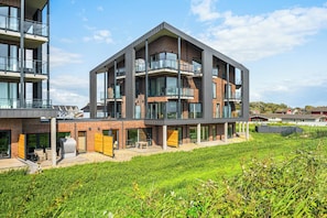 Ein modernes mehrstöckiges Gebäude mit Balkonen, großen Fenstern und einem Flachdach.