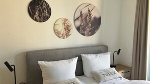 Una cama con dos almohadas, una mesita de noche con una lámpara y una decoración en la pared.