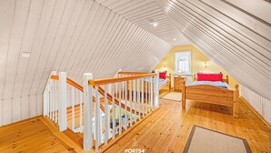 Ein Schlafzimmer mit Holzboden, einem Bett mit Kopfteil, einer weißen Geländer und einem Fenster.