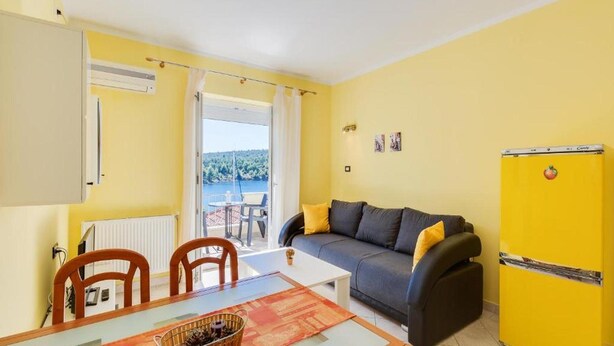 Un espacio habitable compacto con una mesa de comedor, un sofá y un refrigerador amarillo.