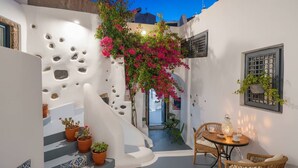 Un patio estrecho con paredes blancas, una escalera y plantas en macetas.