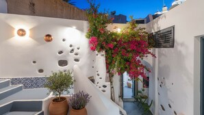 Un edificio de paredes blancas con una escalera, una planta en maceta y un aplique de pared.