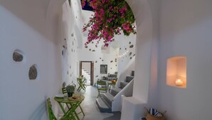 Un interior moderno con paredes blancas, una escalera y una zona de comedor con sillas verdes y una mesa.