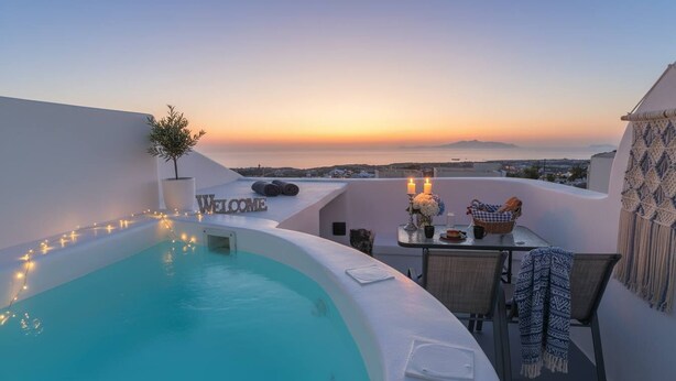 Una piscina en la azotea con vista al atardecer, un cartel de bienvenida y una mesa con velas y una cesta.