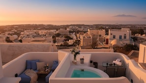 A rooftop terrace with a pool, seating area, and a view of a coastal town.