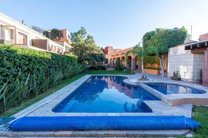 Ein Swimmingpool mit blauer Matte, umgeben von Grünflächen und Gebäuden.