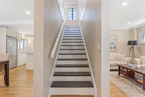 A staircase leading to a second floor with a kitchen and living area visible on the first floor. - Metawisebnb Waterfront 3BR Coastal Escape (Deception Bay)