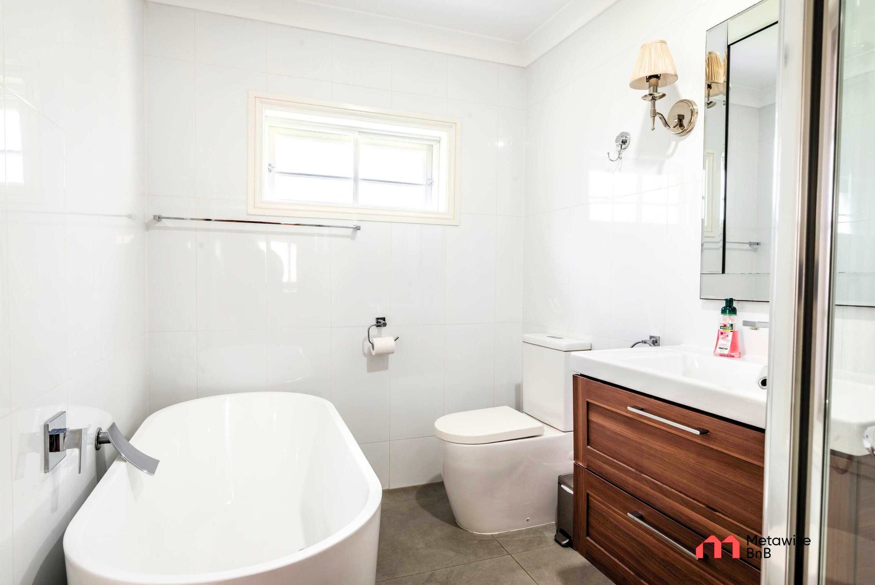 A modern bathroom with a freestanding bathtub, a toilet, and a vanity with a mirror.