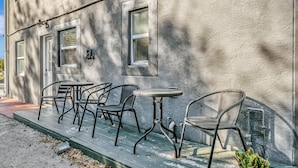 En byggnadsfasad med en veranda, utomhusmöbler och en krukväxt.
