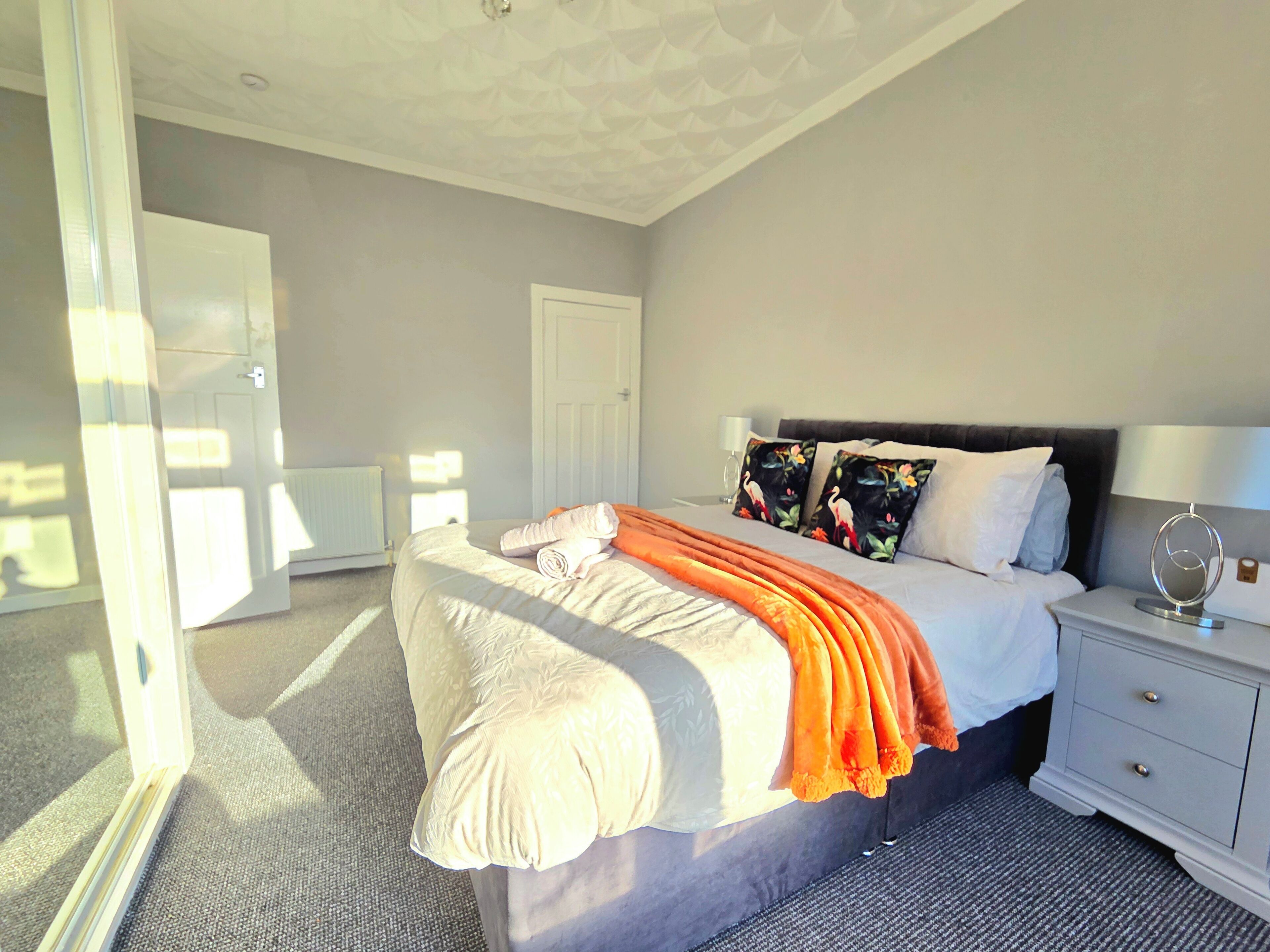 Een slaapkamer met een bed, nachtkastje en een deur.