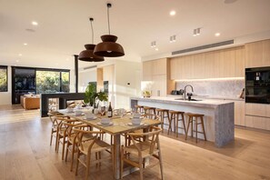 A modern kitchen with wooden cabinets, a marble countertop, and pendant lighting. - The Luxe Seabreeze Heated Pool Spa Cinema (Melbourne)