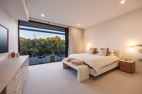 A modern bedroom with a large bed, a desk, and a view of greenery outside. - The Luxe Seabreeze Heated Pool Spa Cinema (Melbourne)