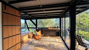 Een modern interieur met een houten vloer, een tapijt met zebraprint en een keukenruimte met uitzicht op de omgeving.