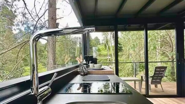 Una cocina moderna con un lavamanos de acero inoxidable y ventana con vista a una terraza.