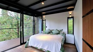 A bedroom with a large bed, a window, and a view of trees. - Room-tranquil Holiday Park Retreat in Gu (Guarne)