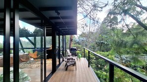A modern outdoor deck with glass walls, wooden flooring, and outdoor furniture. - Room-tranquil Holiday Park Retreat in Gu (Guarne)