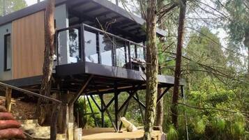 A modern house built on stilts in a forested area.