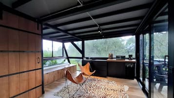 A modern kitchen with a large window, a wooden bench, and a zebra-patterned rug.