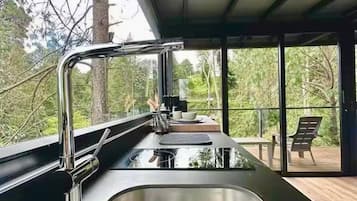 Uma cozinha moderna com uma pia de aço inoxidável e uma janela com vista para um terraço.