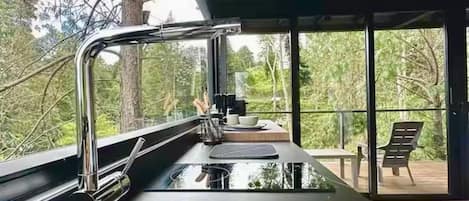 A modern kitchen with a stainless steel sink and a window overlooking a deck.