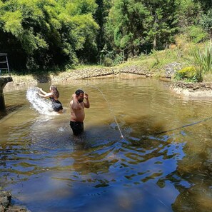 Two people playing in a shallow water body surrounded by greenery. - Cabin in Guarne Nature, Comfort, and Adventure (Guarne)