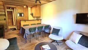 Uma sala de estar acolhedora com área de jantar, teto de madeira e televisão de tela plana.