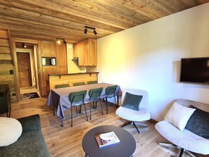 Ein gemütliches Wohnzimmer mit Essbereich, Holzboden und einem Flachbildfernseher.