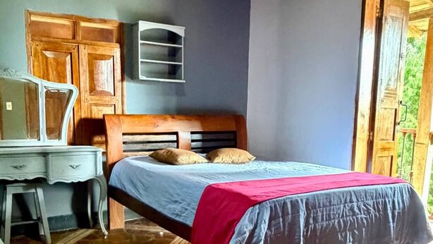 A bedroom with a bed, wooden desk, and a stone-patterned floor. - Tranquil Villa Retreat Near Medellin With Private Pool (Guarne)
