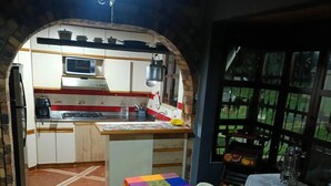 A compact kitchen with a tiled floor, a dining table with chairs, and a window with a view of greenery. - Tranquil Villa Retreat Near Medellin With Private Pool (Guarne)