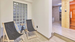 Quarto com duas cadeiras de tela, uma janela ampla com vista e uma porta de madeira para uma área de chuveiro.