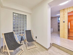 A room with two canvas chairs, a large window with a view, and a wooden door leading to a shower area.