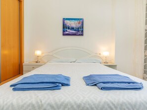 A hotel room with a bed, two bedside lamps, a painting on the wall, and two folded towels on the bed.