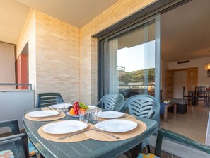 A dining area with a table set for four, chairs, and a view through a glass door.