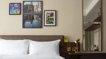 A hotel room with a bed, a nightstand, a mirror, and three framed pictures on the wall.