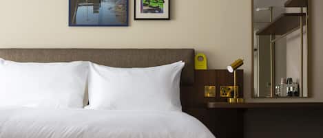 Una habitación de hotel con una cama, una mesita de noche, un espejo y tres cuadros en la pared.
