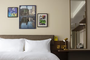 Una habitación de hotel con una cama, una mesita de noche, un espejo y tres cuadros en la pared.