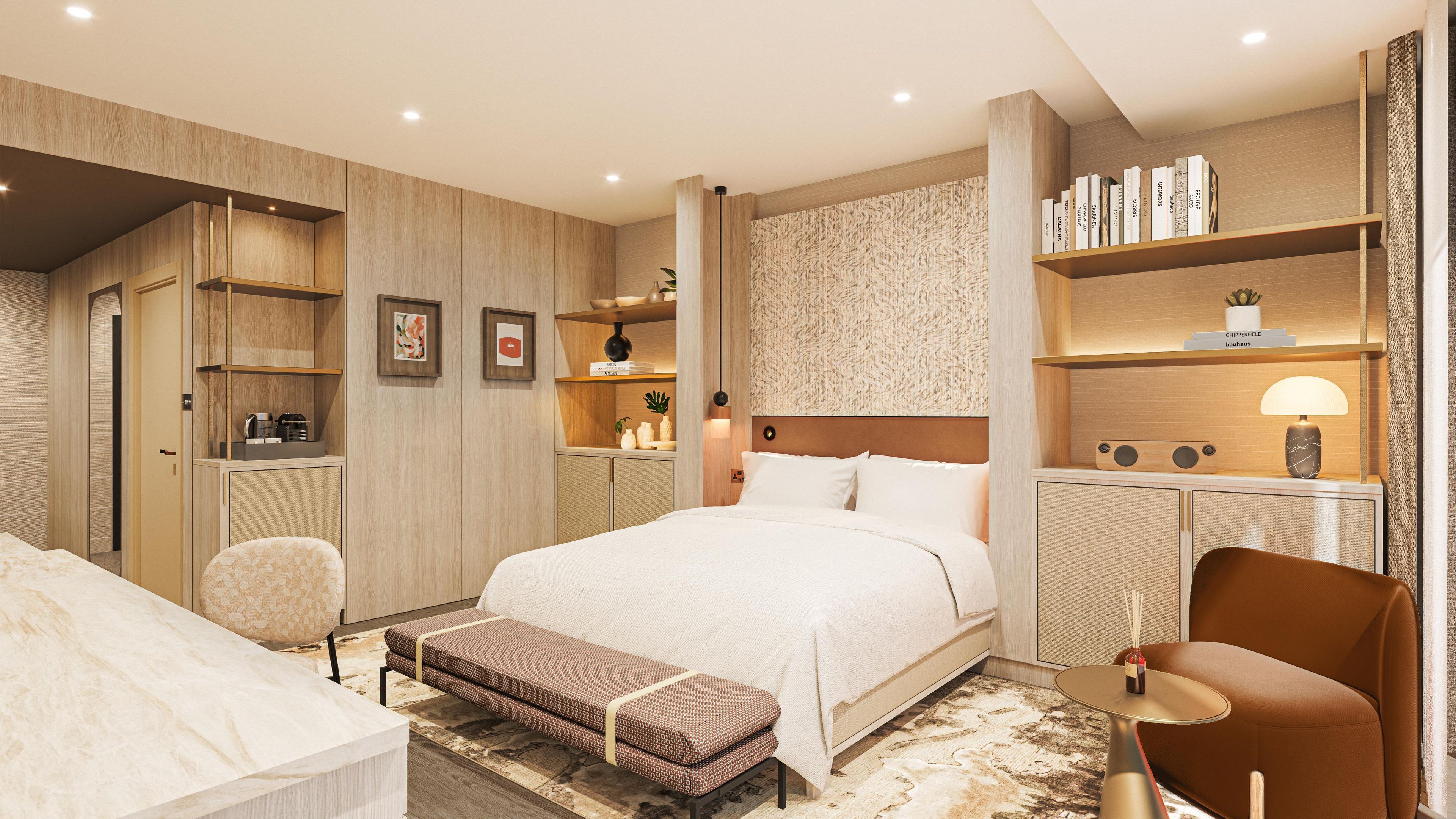 A modern hotel room with a large bed, a sitting area with a bench, a desk, and a bookshelf.