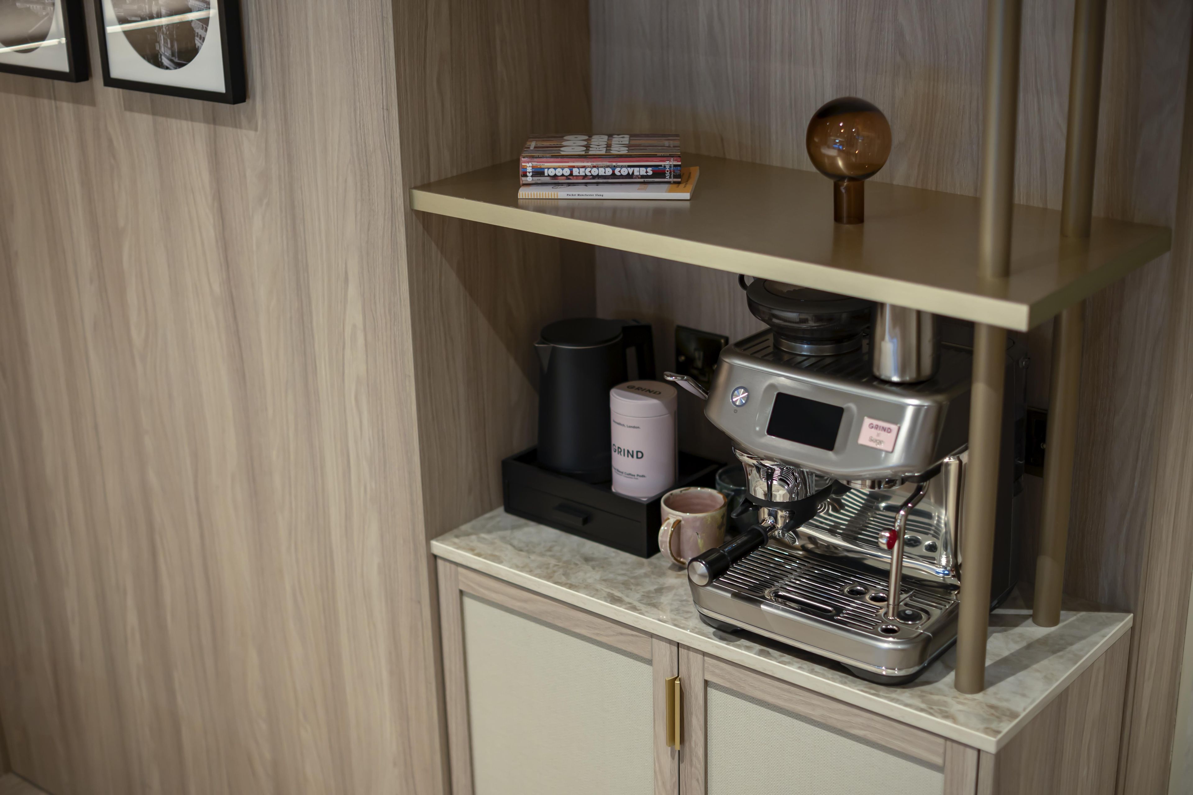 A coffee machine on a countertop with a coffee grinder and a mug.