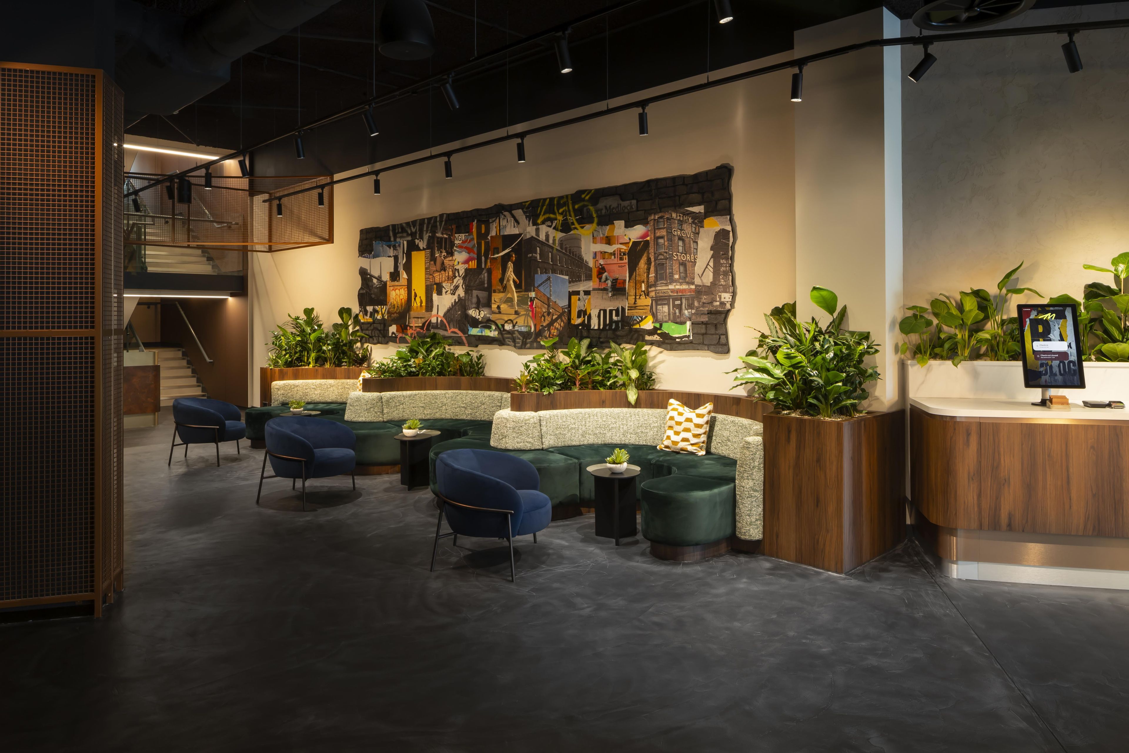 A modern interior with a seating area, a large abstract mural, and a reception desk with a digital display.