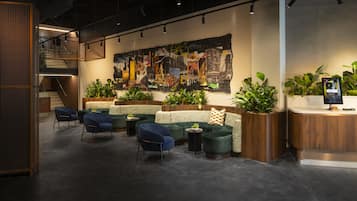 A modern interior with a seating area, a large abstract mural, and a reception desk with a digital display.