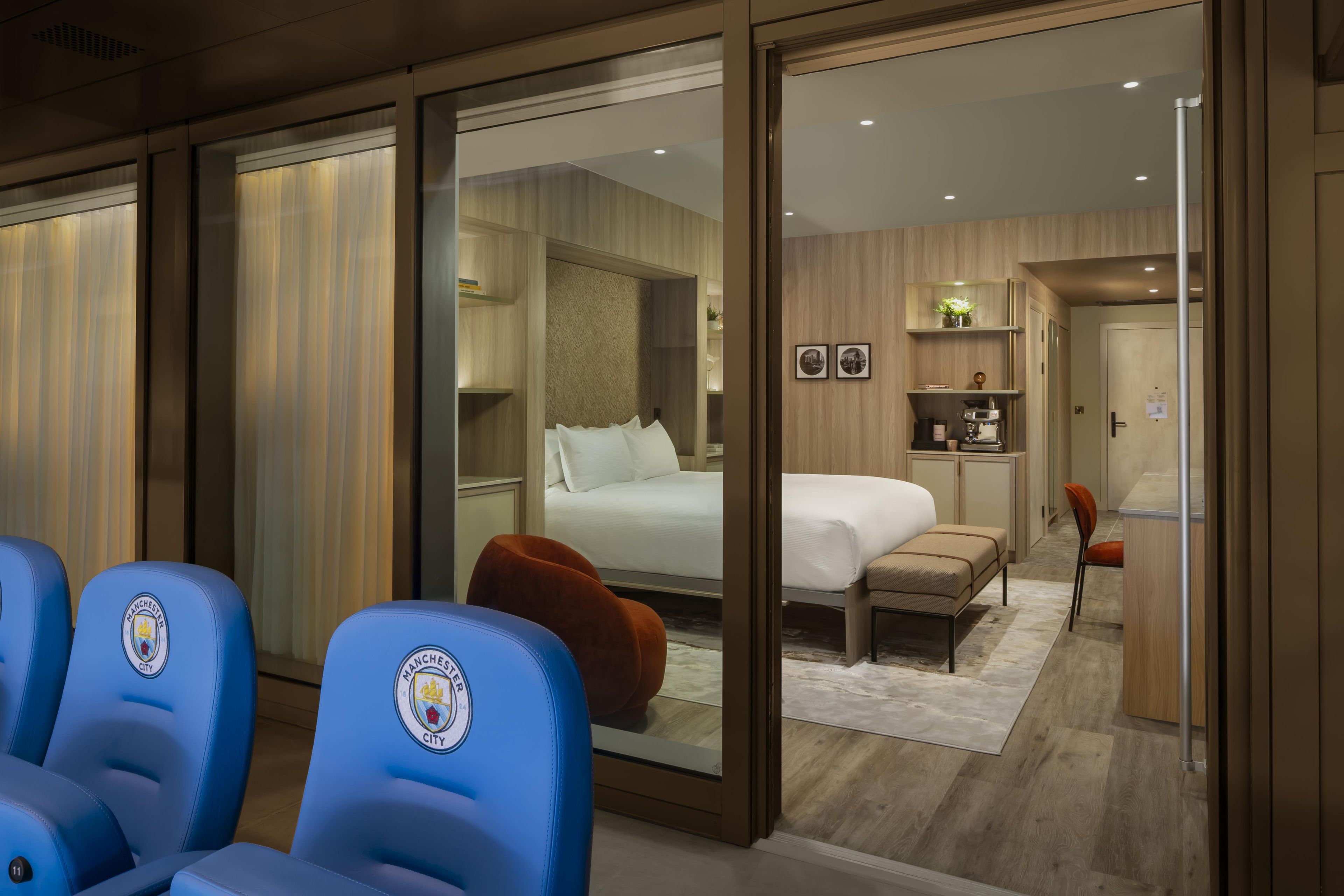 Quarto de hotel com cama, escrivaninha, poltrona e sofá.