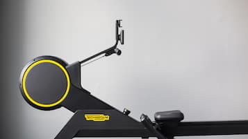 A stationary exercise machine with a handle, a seat, and a control panel.
